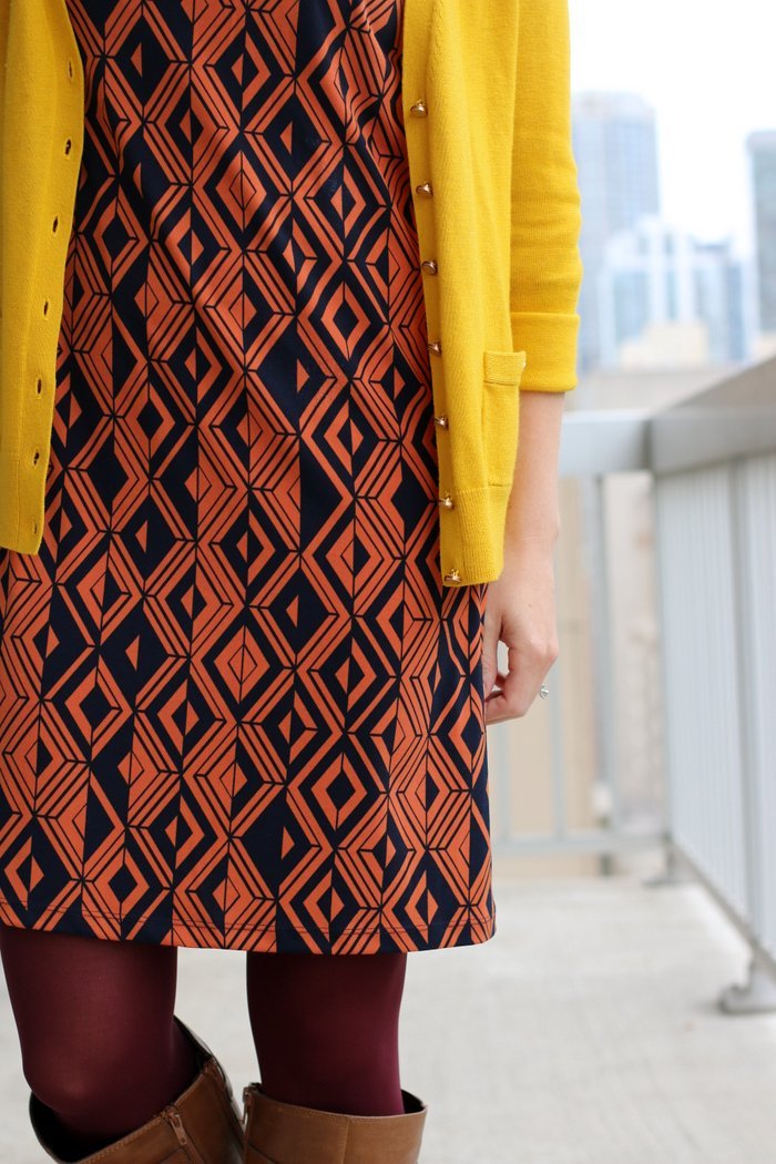 FashionablyEmployed.com | Orange and navy geometric print dress, maroon tights, mustard cardigan and cognac boots | wear to work outfit, office style, workwear