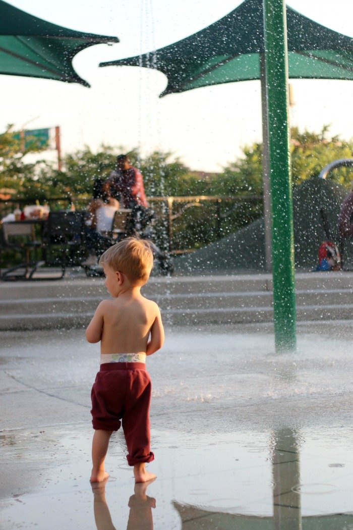 little boy in the water fountain at a city water park