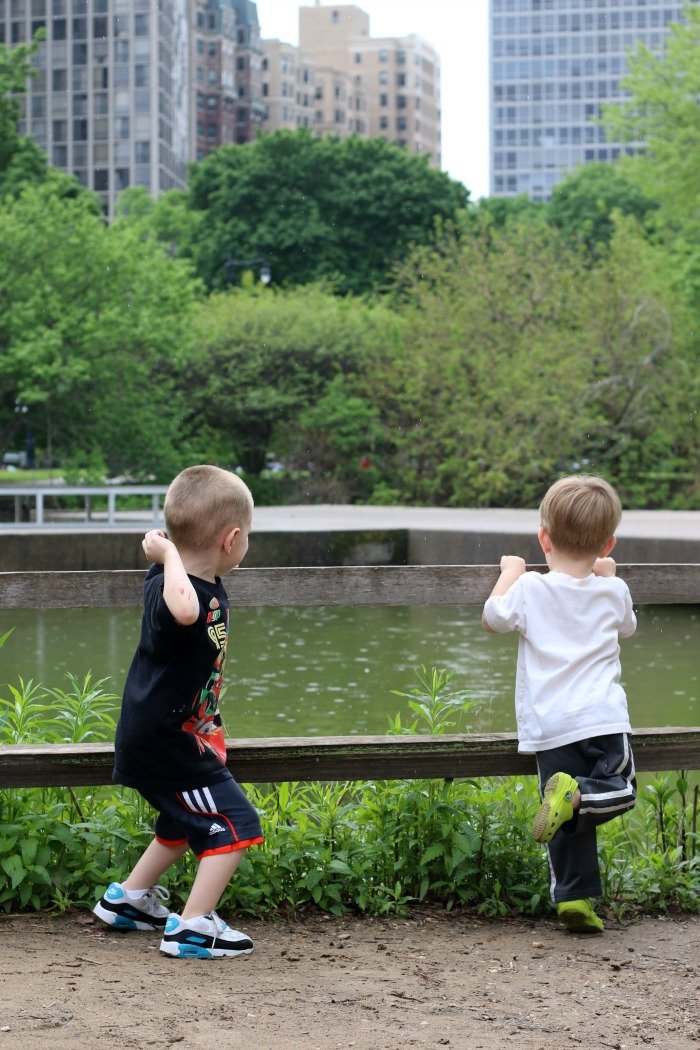 two boys throwing rocks into a pond