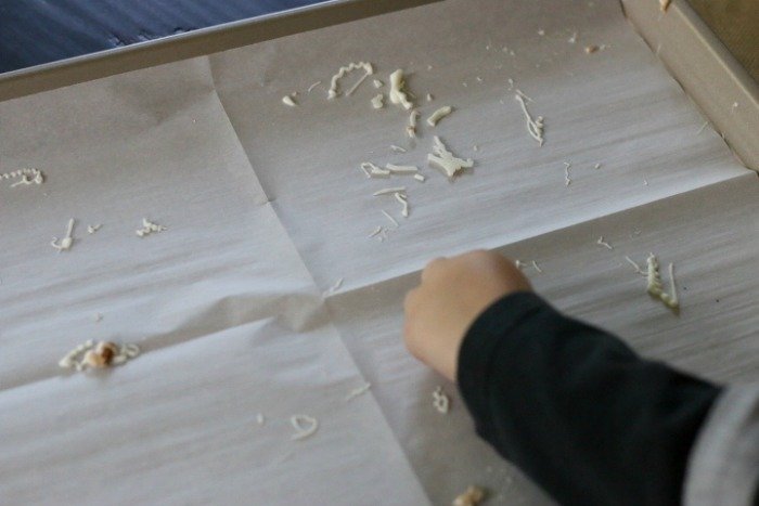 little boy eating white chocolate crumbs from a tray