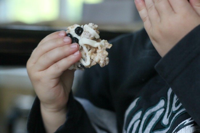 little boy holding white chocolate blueberry clusters