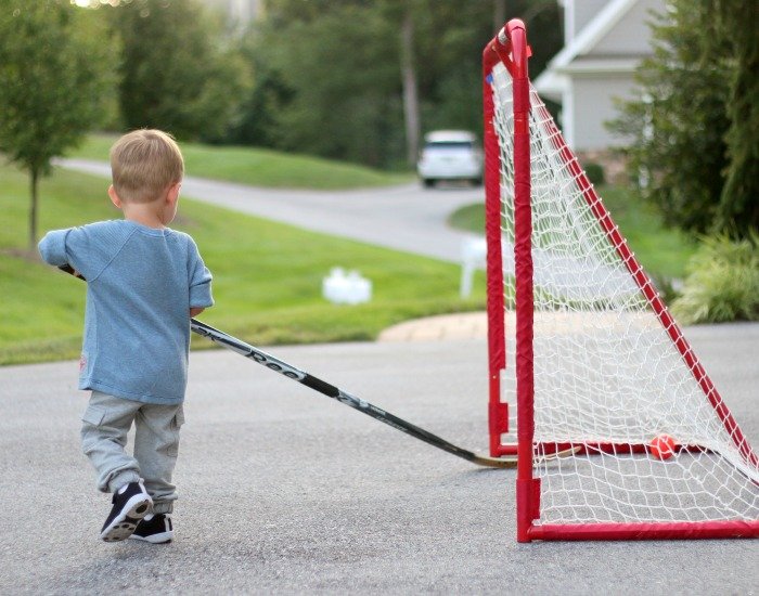 little boy playing hockey i nhis driveway