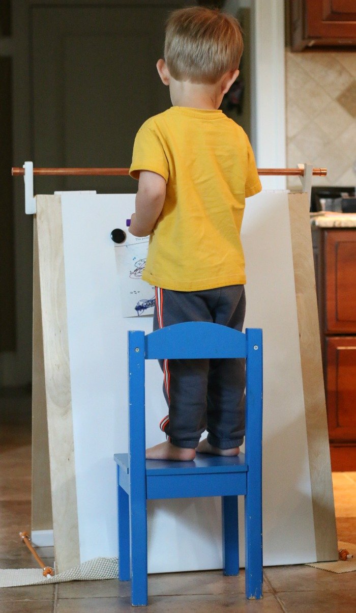 little-boy-standing-on-a-chair-and-coloring-on-a-handmade-easel