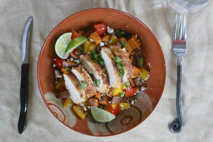 southwestern spiced chicken with peppers sweet potatos and lime wedges in a bowl