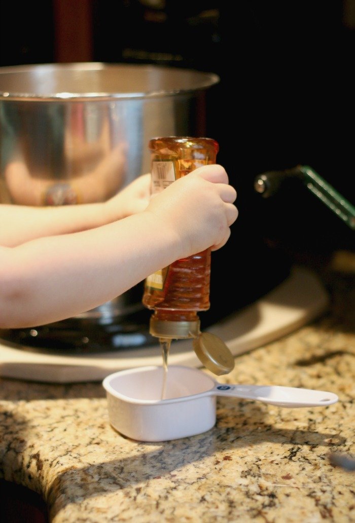 little-hands-squeezing-honey-into-a-cup-for-baking