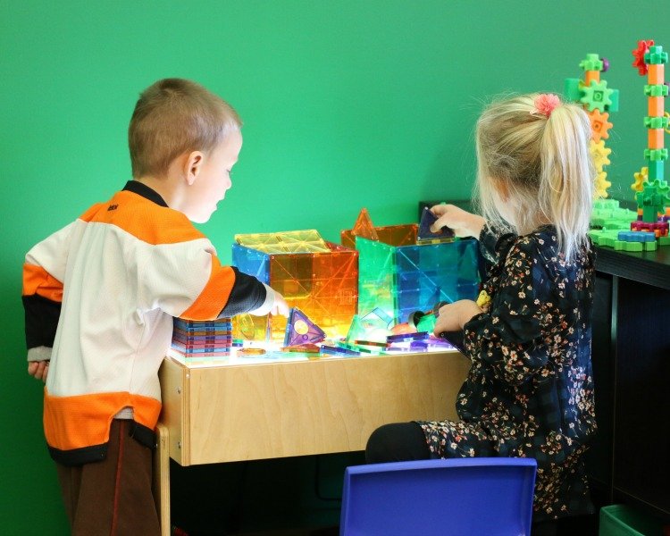 two children playing with Magnatiles on a table