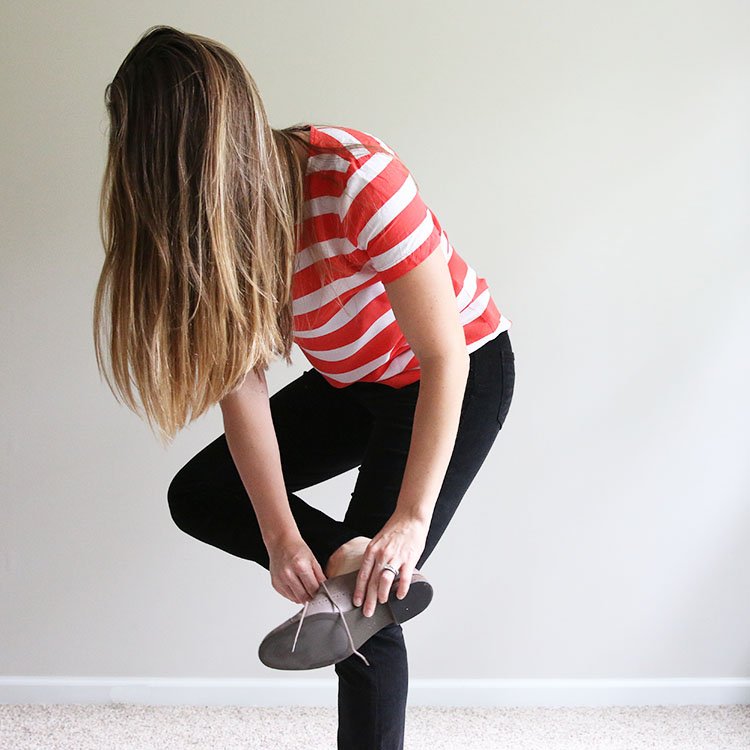 woman in orange and white striped shirt putting on shoes