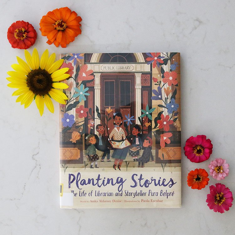 Planting Stories book on a counter next to yellow and pink flowers