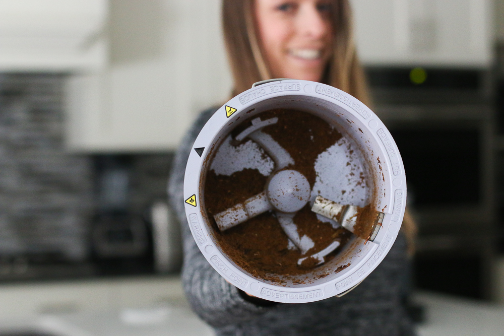 Woman holding food cycler bucket in front of her to show the inside with processed Foodilizer inside of it. 