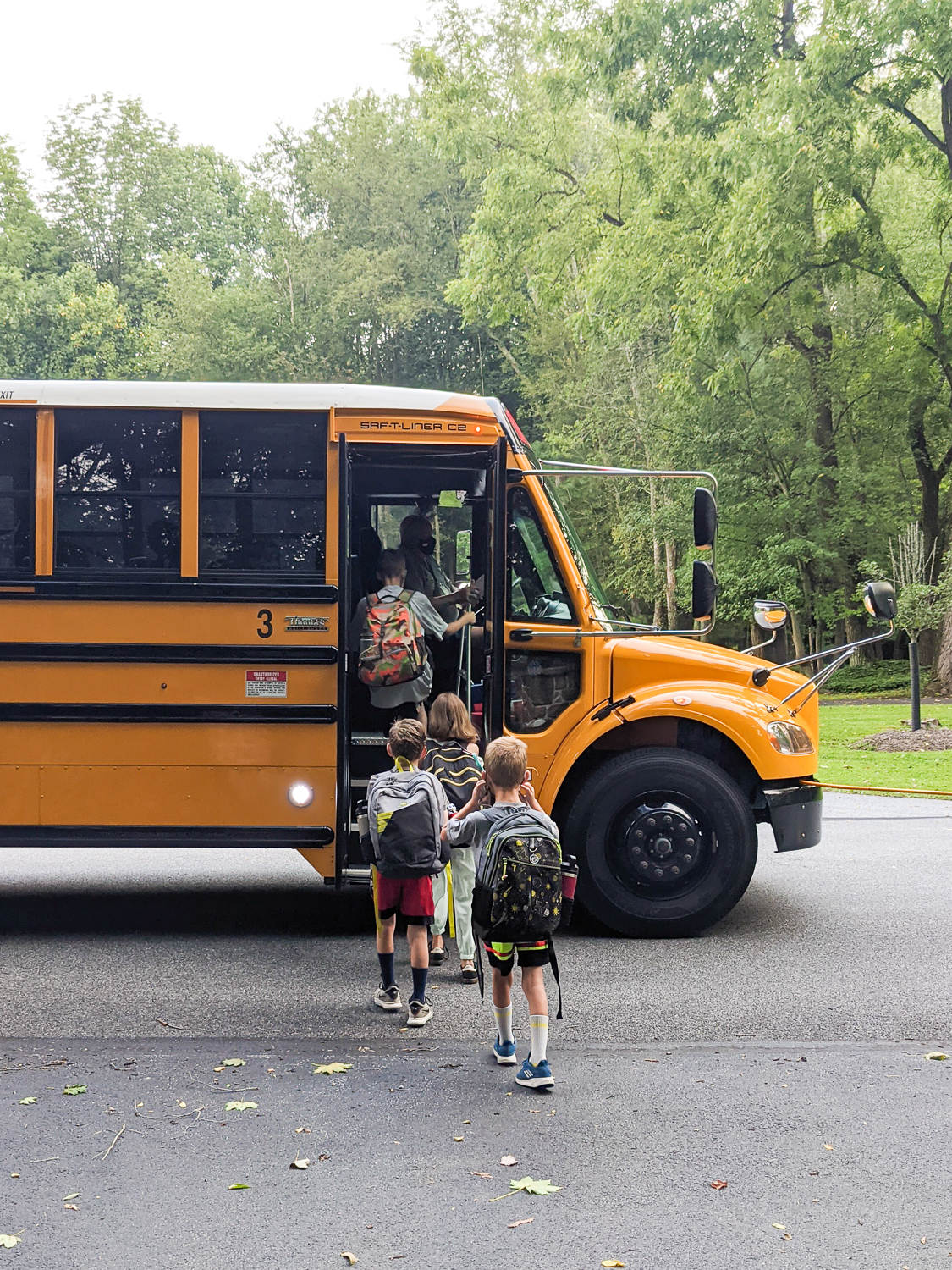 four kids boarding a school bus