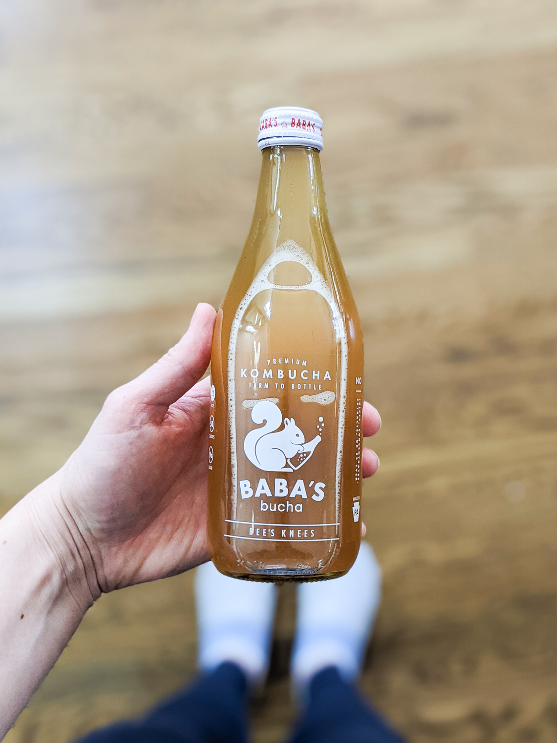 hand holding a bottle of Baba's Bucha in Bees Knees flavor