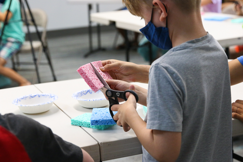 child cutting a sponge to build a sprout house