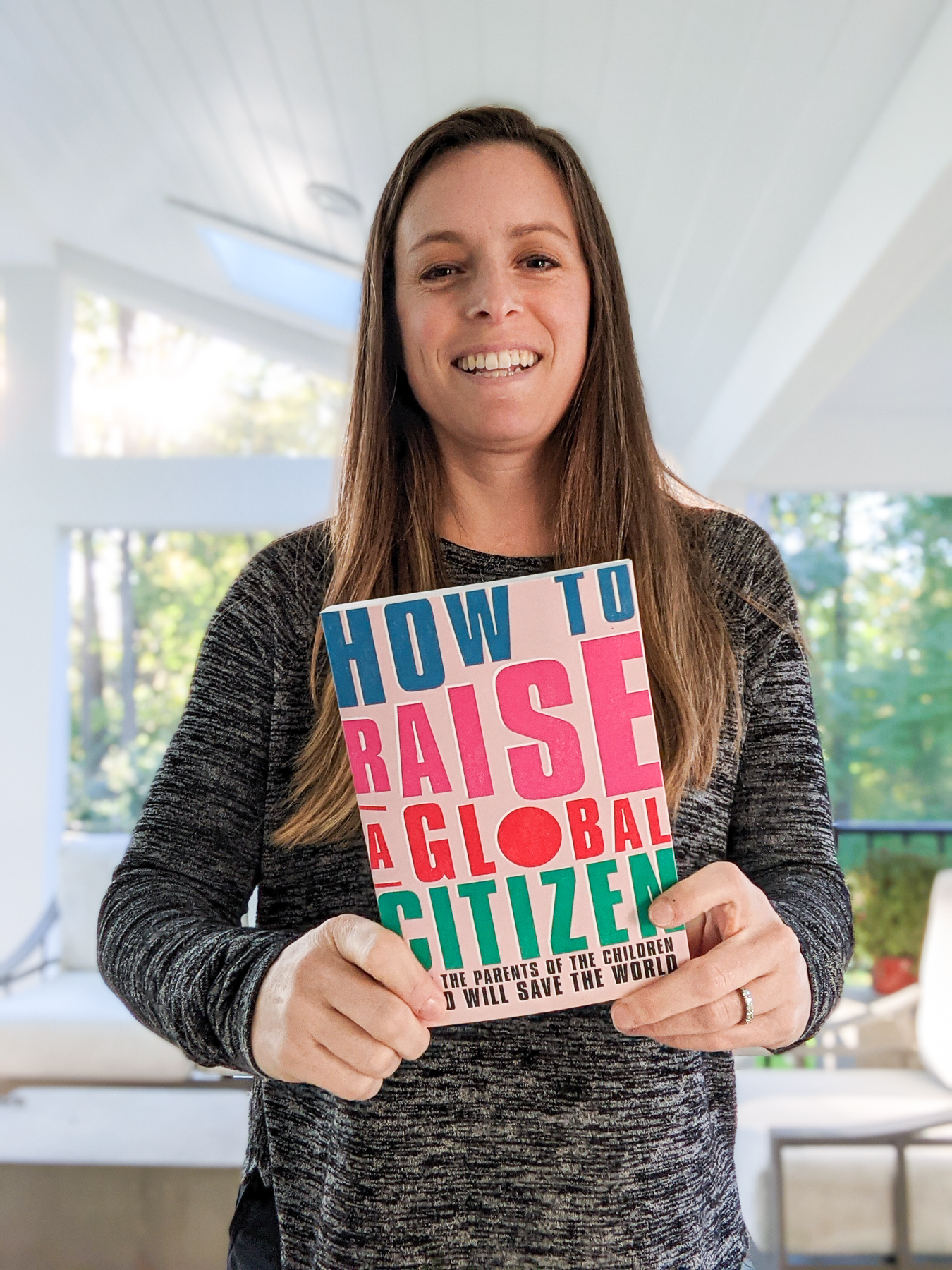 Jen holding the book she was published in, How to raise a global citizen