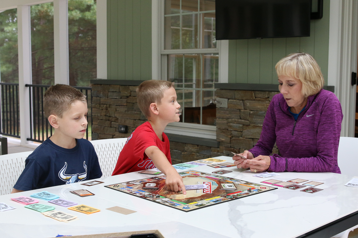 Grandmother and two boys playing National Parks Monopoly outside on a table