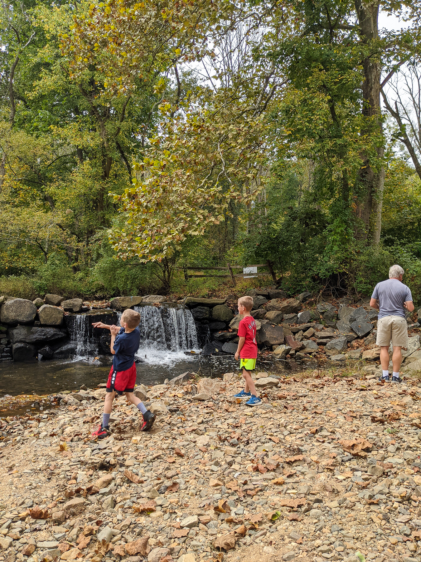 Grandfather and two boys at Newlin Gist Mill throwing rocks into water
