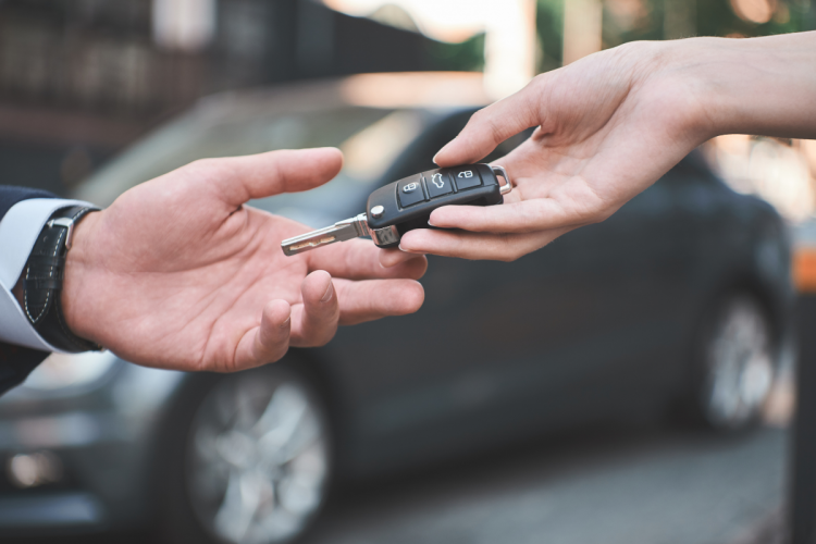 Two hands passing a car key