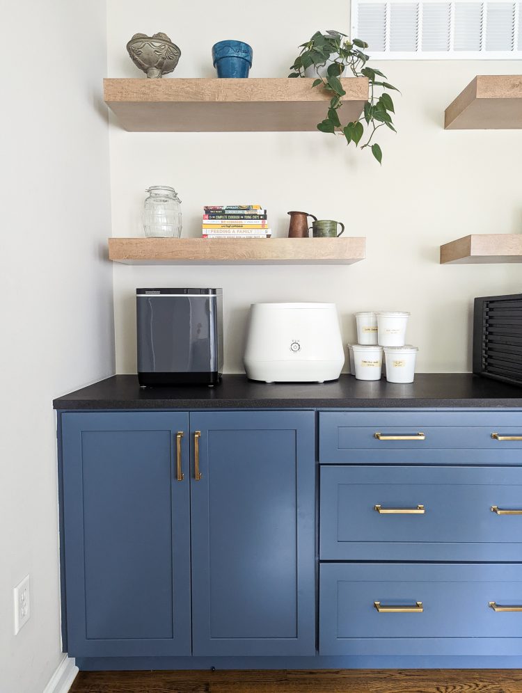 Lomi kitchen composter and Vitamix FoodCycler on a black counter over blue cabinets
