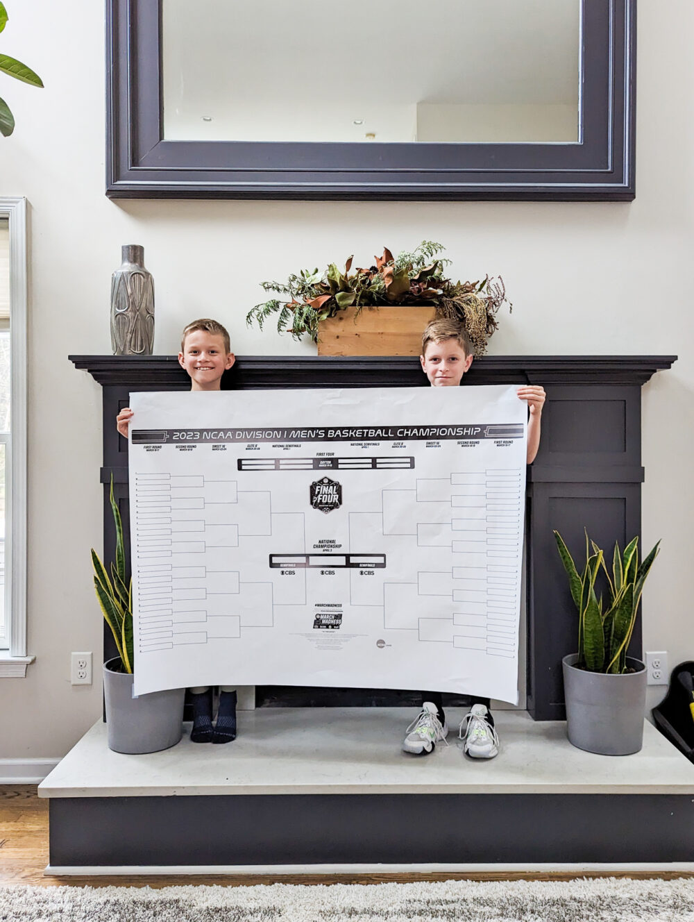 two boys holding a large march madness bracket